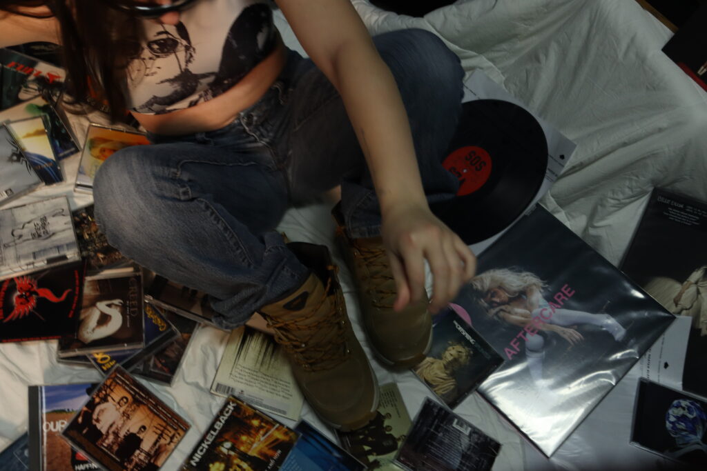 Une femme assise dans une pile de cd et vinyles